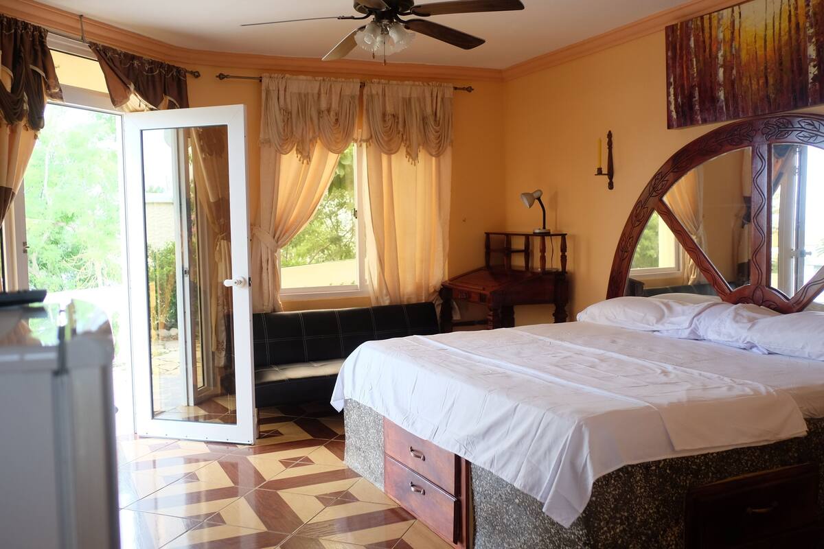 Un dormitorio con cama, escritorio, silla y ventana con cortinas.