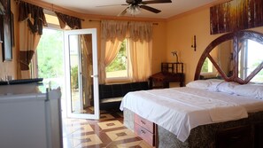 A bedroom with a bed, a desk, a chair, and a window with curtains. - Jardines del Paraiso (Tola)