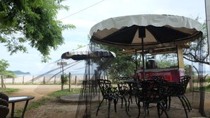 An outdoor seating area with a covered table and chairs, a grill station, and a view of the beach and ocean. - Jardines del Paraiso (Tola)