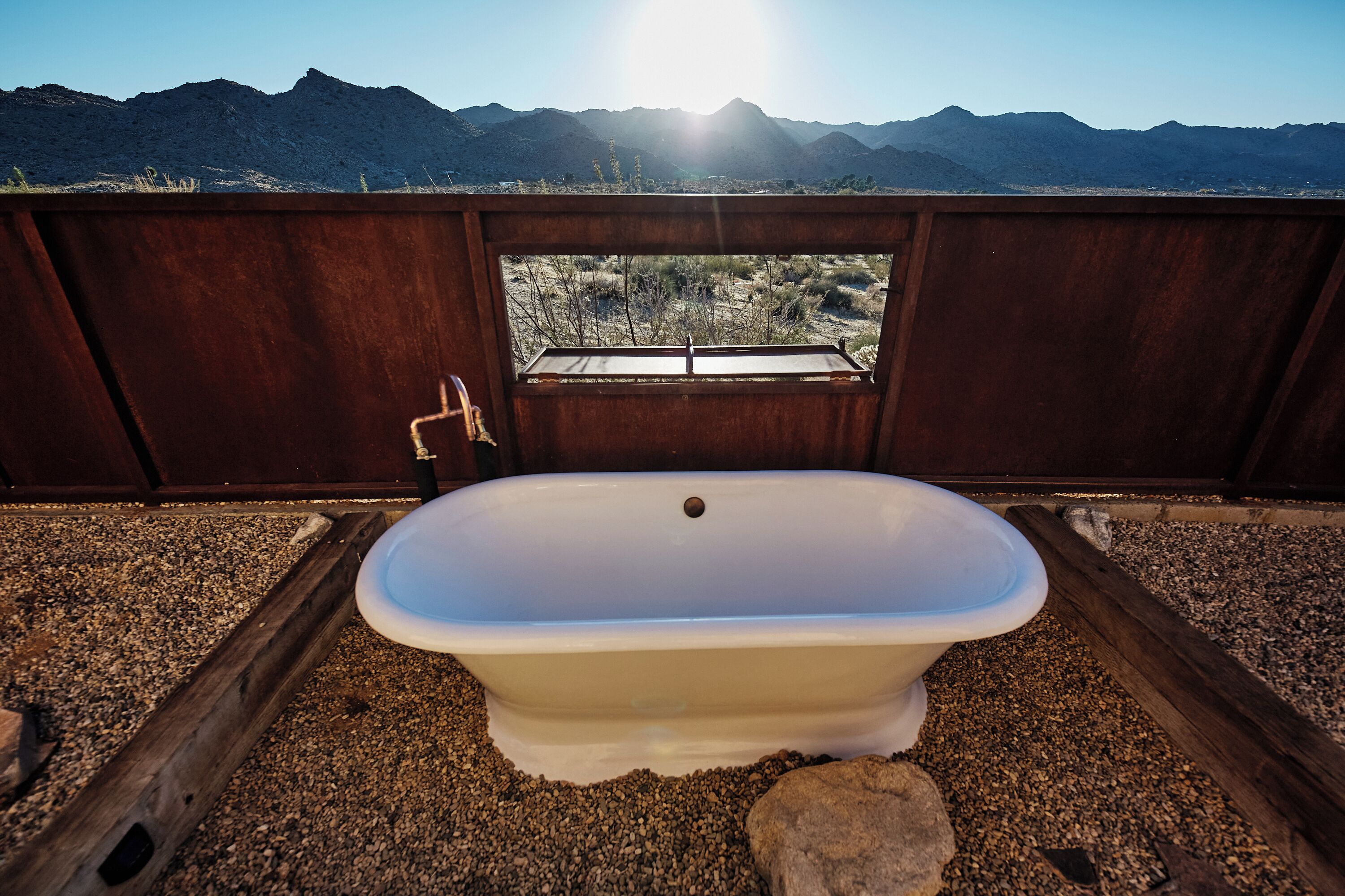 Una bañera en un entorno rústico con vistas a montañas.