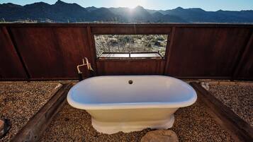 Una bañera en un entorno rústico con vistas a montañas.