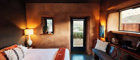 A bedroom with a bed, bedside lamp, and a bench with cushions.