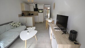 A compact living space with a sofa, a dining table, a TV, and a kitchen area. - T2 + AIR-CONDITIONED Cabin CROSSING 2 TERRACES 400 meters from the sea (BORMES-LES-MIMOSAS)