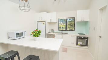 A modern kitchen with white cabinetry, a microwave, a coffee maker, and a potted plant.