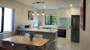 Una cocina moderna con una isla central, una zona de comedor con mesa y sillas, y un refrigerador.
