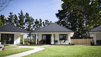 A modern two-story house with a covered patio, a lawn, and a wooden fence.