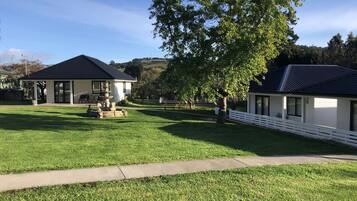Una propiedad residencial con un césped cuidado, una fuente de piedra y una valla blanca.