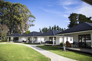A row of two-story houses with a covered patio area, a lawn, and a pathway leading to the entrance.