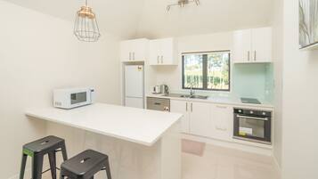 A modern kitchen with white cabinets, a microwave, a coffee maker, and a window.