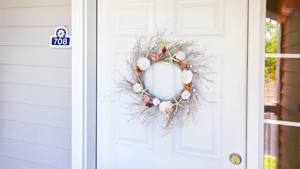 Uma porta branca com uma grinalda decorativa.