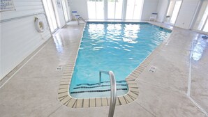 Uma piscina interior com água cristalina, um boi de salvamento e uma escada de piscina.