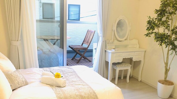 Un dormitorio con cama, escritorio, silla y planta en maceta.