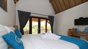 Una habitación de hotel con una cama grande, un escritorio con una silla, un televisor y un balcón con cortinas.