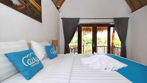 Un dormitorio con una cama grande, dos almohadas, un cuadro en la pared y vistas a zonas verdes.