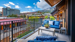 Ein Balkon mit Holzboden, einem Sofa mit blauen Kissen, einem kleinen Tisch und einem Blumentopf.