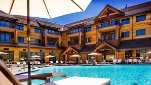 Ein mehrstöckiges Holzgebäude mit Schwimmbad, Außenbereich mit Sitzgelegenheiten und einer überdachten Terrasse.