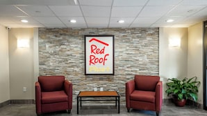 A reception area with a stone wall, two red chairs, a wooden table, and a potted plant.