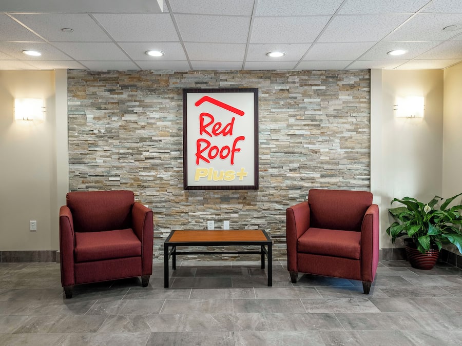 A reception area with a stone wall, two red chairs, a wooden table, and a potted plant.
