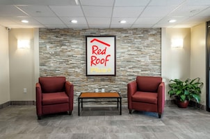 A reception area with a stone wall, two red chairs, a wooden table, and a potted plant.