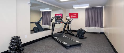 Une chambre d’hôtel équipée d’un tapis de course, d’un vélo d’appartement et d’un ensemble d’haltères.