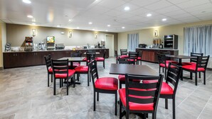 A hotel dining area with multiple tables and chairs, a coffee machine, and a buffet station. - Red Roof Inn PLUS+ Tuscaloosa - University (Tuscaloosa)
