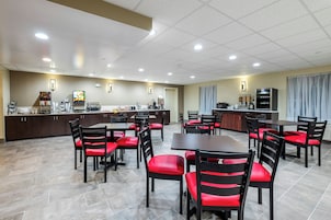 A hotel dining area with multiple tables and chairs, a coffee machine, and a buffet station.
