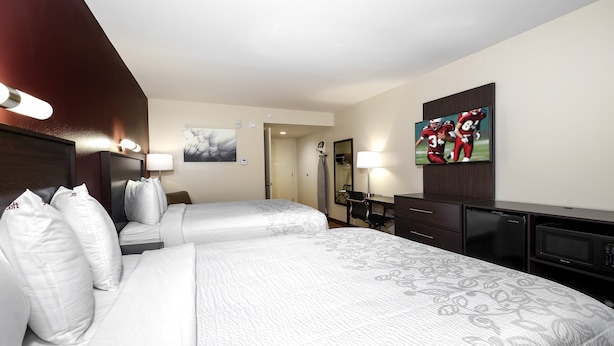 A hotel room with two beds, a desk, a television, and a minibar.