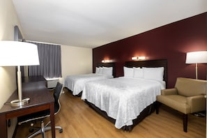 A hotel room with two beds, a desk, a chair, and a desk lamp. - Red Roof Inn PLUS+ Tuscaloosa - University (Tuscaloosa)