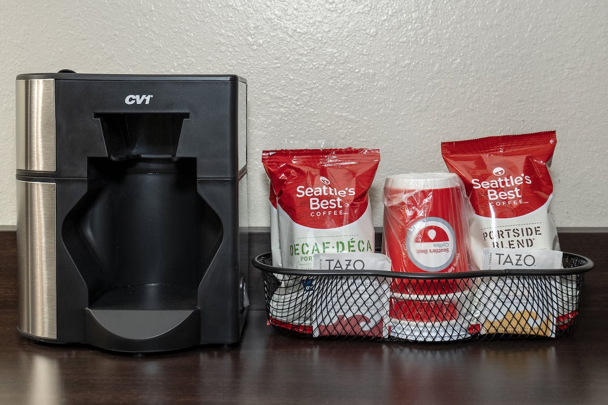A coffee maker and bags of Seattle's Best coffee on a table.