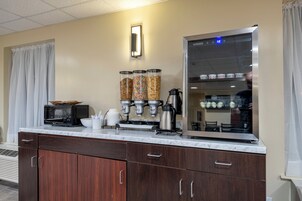 A kitchenette with a microwave, coffee maker, and cereal dispensers.