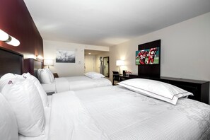 A hotel room with two beds, a desk, a chair, a TV, and a painting on the wall. - Red Roof Inn PLUS+ Tuscaloosa - University (Tuscaloosa)