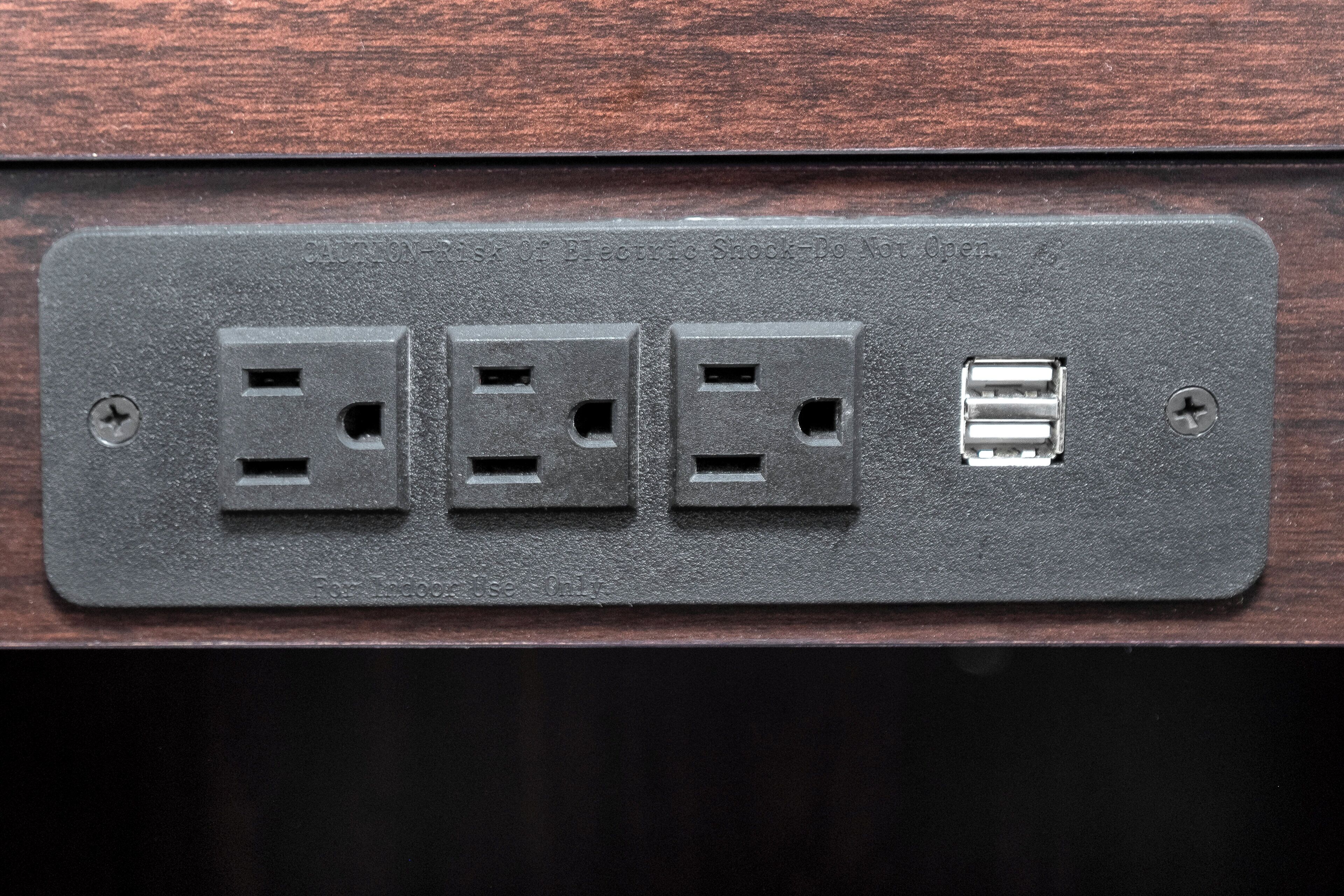 A wall-mounted electrical outlet with three standard sockets and one USB port.