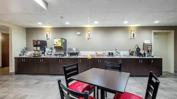 Un espace cuisine moderne avec une table et des chaises, équipé de machines à café et d’un grille-pain.