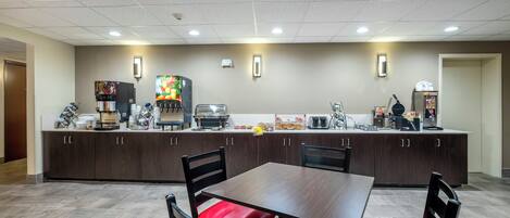 A modern kitchen area with a dining table and chairs, equipped with coffee machines and a toaster.