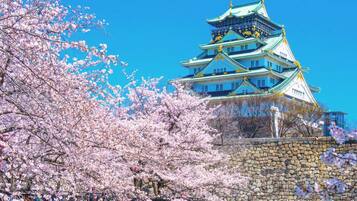 A traditional Japanese castle with multiple tiers, surrounded by cherry blossom trees.