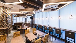 A modern restaurant interior with a curved seating area, wooden tables, and a mosaic wall. - Astil Hotel Juso Precious (Osaka)