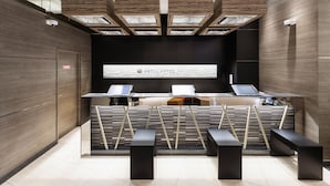 A reception desk with two laptops, a wooden wall, and a tiled floor. - Astil Hotel Juso Precious (Osaka)