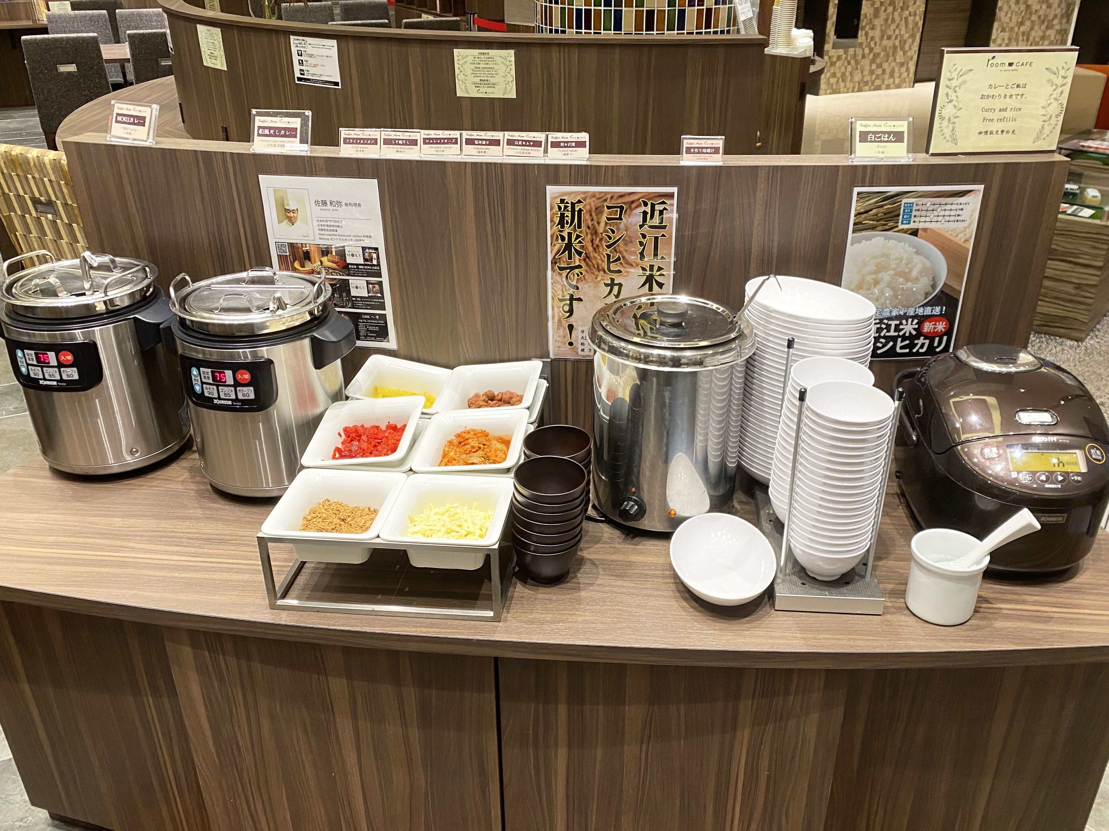 Un comptoir de buffet avec différents récipients contenant divers aliments, notamment du riz, des nouilles et des légumes.