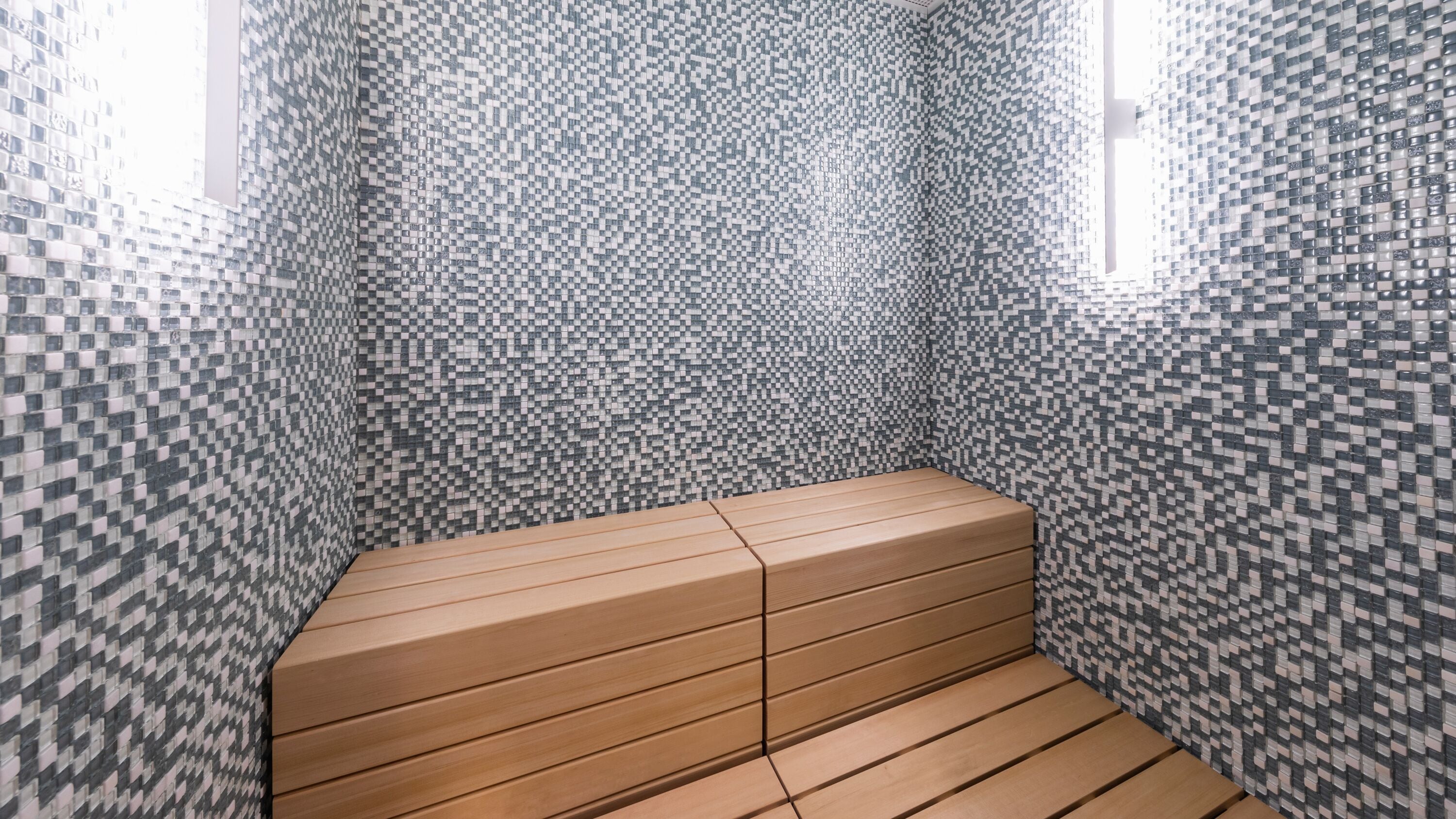 A small, enclosed space with a checkered tile wall and a wooden bench.