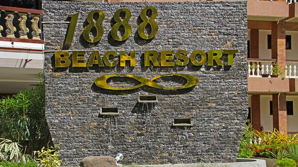 En stenmur med texten ”1888 Beach Resort” och en oändlighetssymbol.