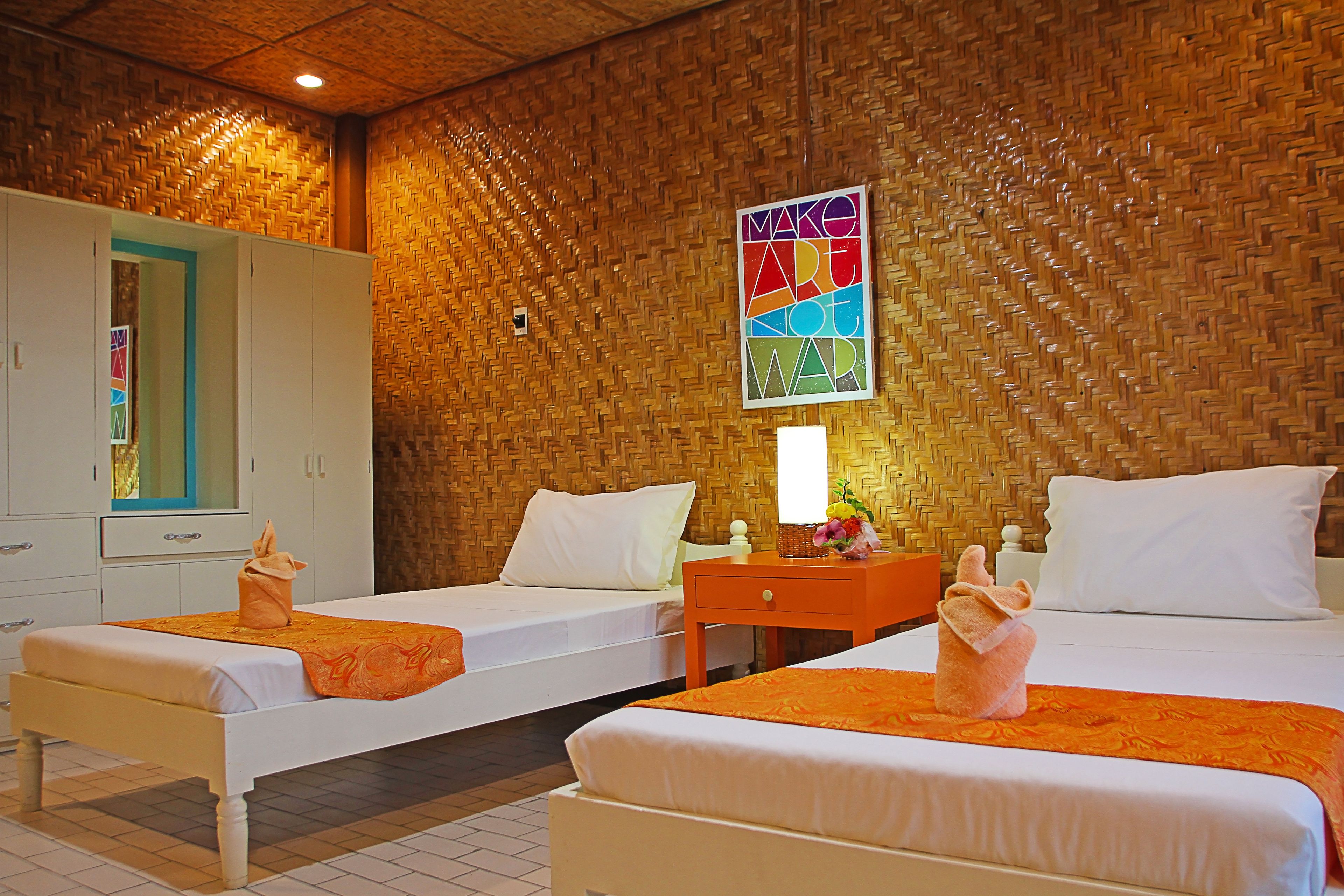 A hotel room with two beds, a wooden wall, a poster, and a wardrobe.