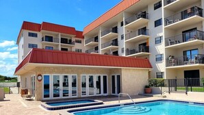 A multi-story building with a swimming pool, outdoor seating, and balconies. - 517 - Nicely Decorated Oceanfront 3 Bedroom (New Smyrna Beach)