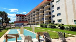 Un hôtel à plusieurs étages doté de balcons, d’une piscine et d’une pelouse bien entretenue.
