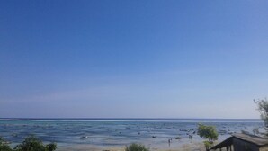 A coastal view with a clear sky, calm sea, and boats. - Kusuma Abiakta (Lembongan Island)