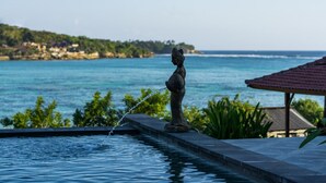 A statue in a pool with a view of the ocean and a building in the background. - Kusuma Abiakta (Lembongan Island)