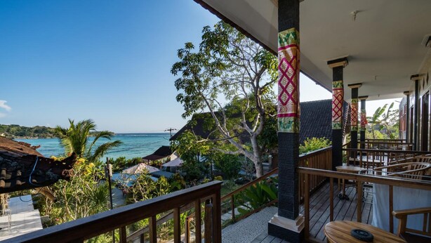 A wooden deck with a view of the ocean, surrounded by tropical vegetation and a thatched-roof structure. - Kusuma Abiakta (Lembongan Island)
