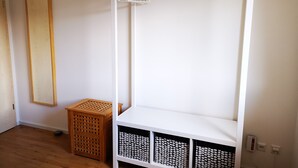 A white wardrobe with a hanging rod and three storage drawers.