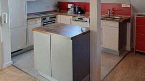 A modern kitchen with a skylight, wooden countertops, and a red accent wall.