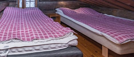 Camera accogliente in una baita di legno, con un letto a soppalco, un letto più piccolo e una finestra vista sulla neve.