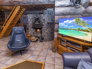 Una sala de estar acogedora con chimenea de piedra, televisión y un sillón cómodo.